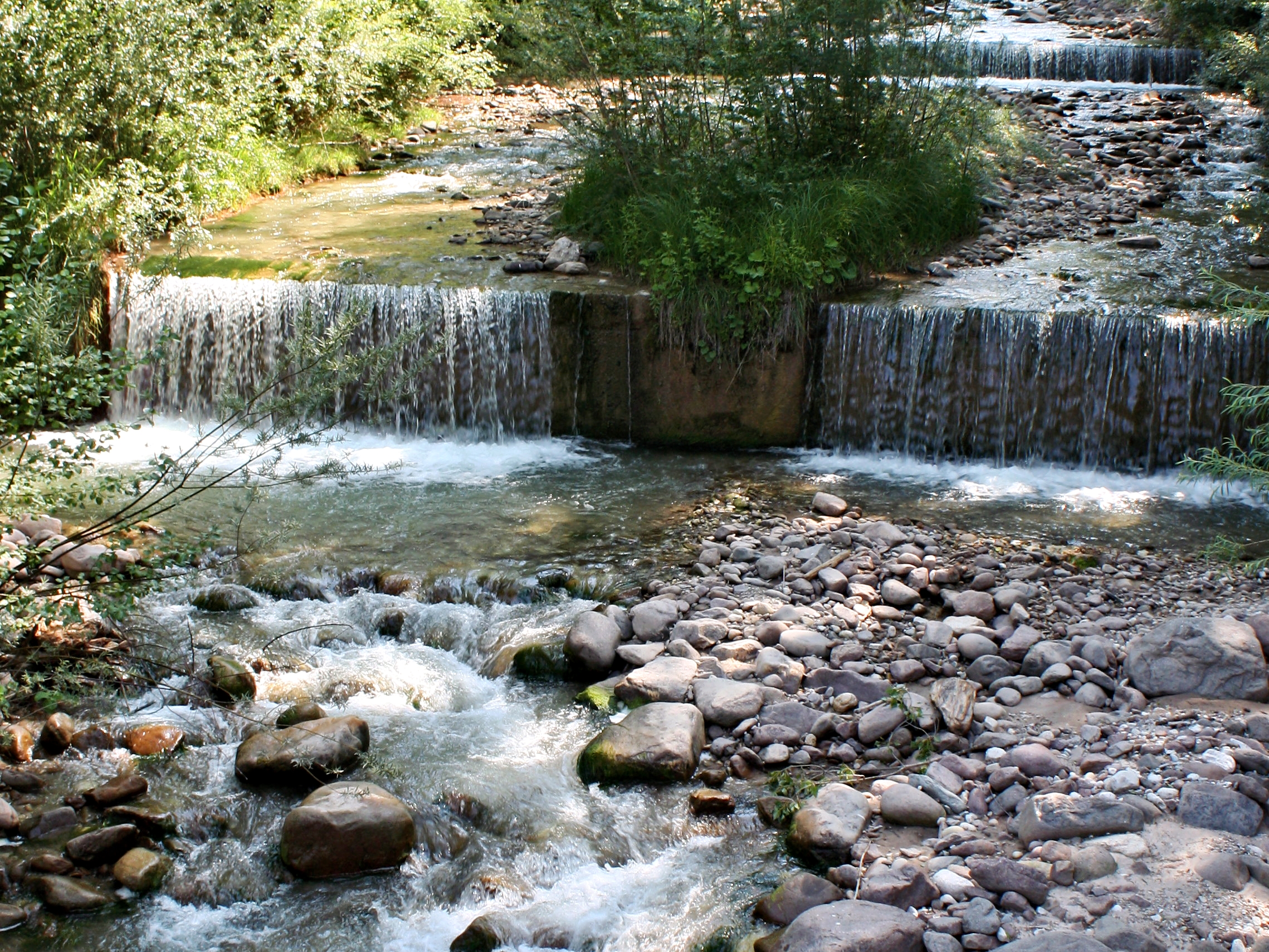 Bachlauf mit kleinen Wasserfällen. Das Wasser fällt wie ein breiter Vorhang (c) k-h. Bachlauf mit kleinen Wasserfällen. Das Wasser fällt wie ein breiter Vorhang